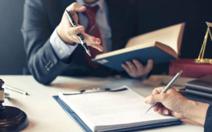 A product liability attorney reviewing paperwork on a desk with a client in Las Cruces.