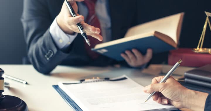 A product liability attorney reviewing paperwork on a desk with a client in Las Cruces.